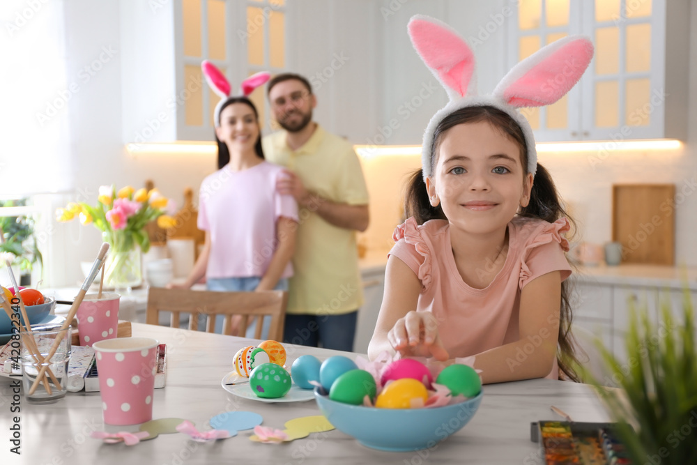 Cute little child painting Easter eggs at table in kitchen Cute little child painting Easter eggs at table in kitchen