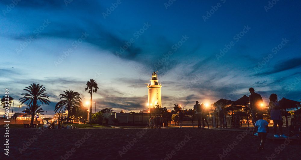 Lighthouse in the old part of the Malaga harbor at dusk