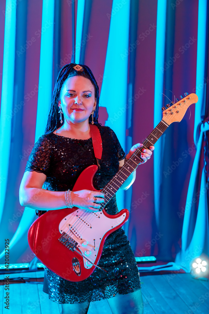 Woman with blue afro hairstyle musician guitarist playing electric guitar at a concert. Woman with blue afro hairstyle musician guitarist playing electric guitar at a concert.