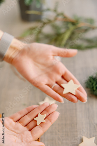 The girl creates New Year s decor. Hands hold five-pointed wooden stars. Winter mood and holidays.