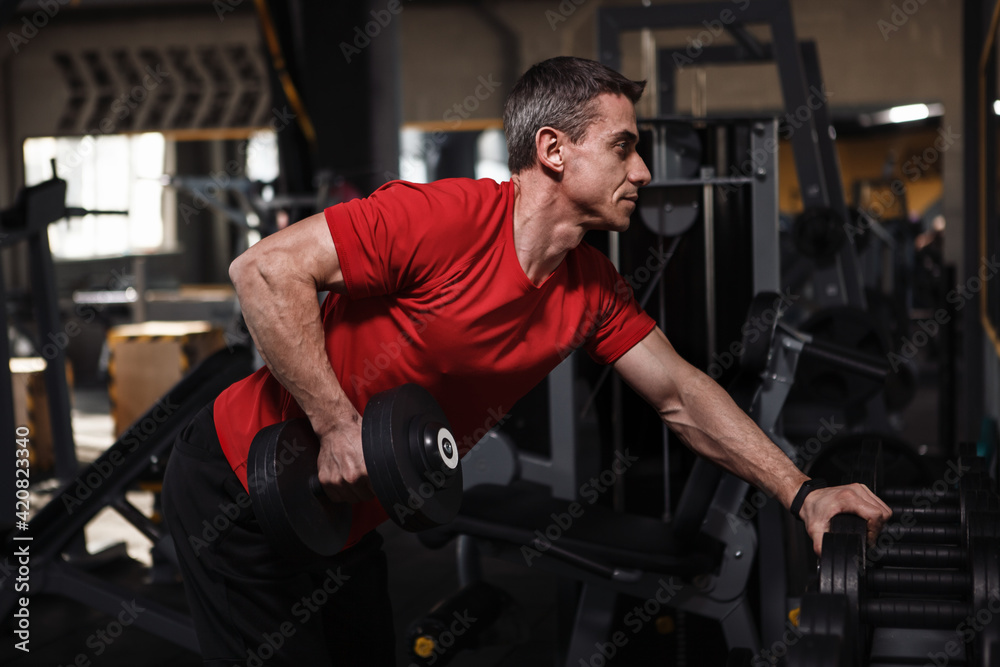 Middle aged sportsman lifting weights at the gym Middle aged sportsman lifting weights at the gym