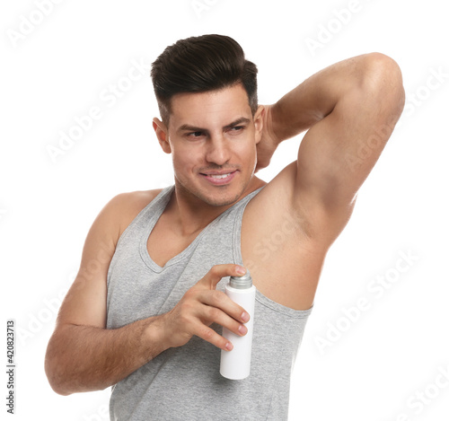 Handsome man applying deodorant to armpit on white background