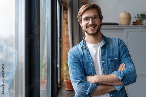 Portrait of smiling young businessman looking at camera in home office.