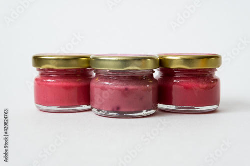 Three jars of fruit jam on white background.