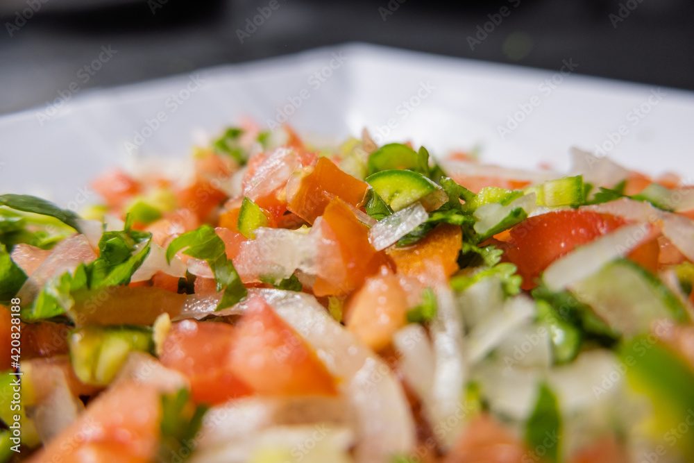 Chopped tomato, onion, and chili pepper on white plate Chopped tomato, onion, and chili pepper on white plate