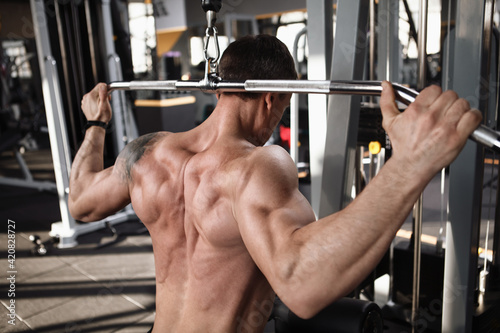 Close up rear view shot of a shirtless ripped sportsman doing back muscles exercise