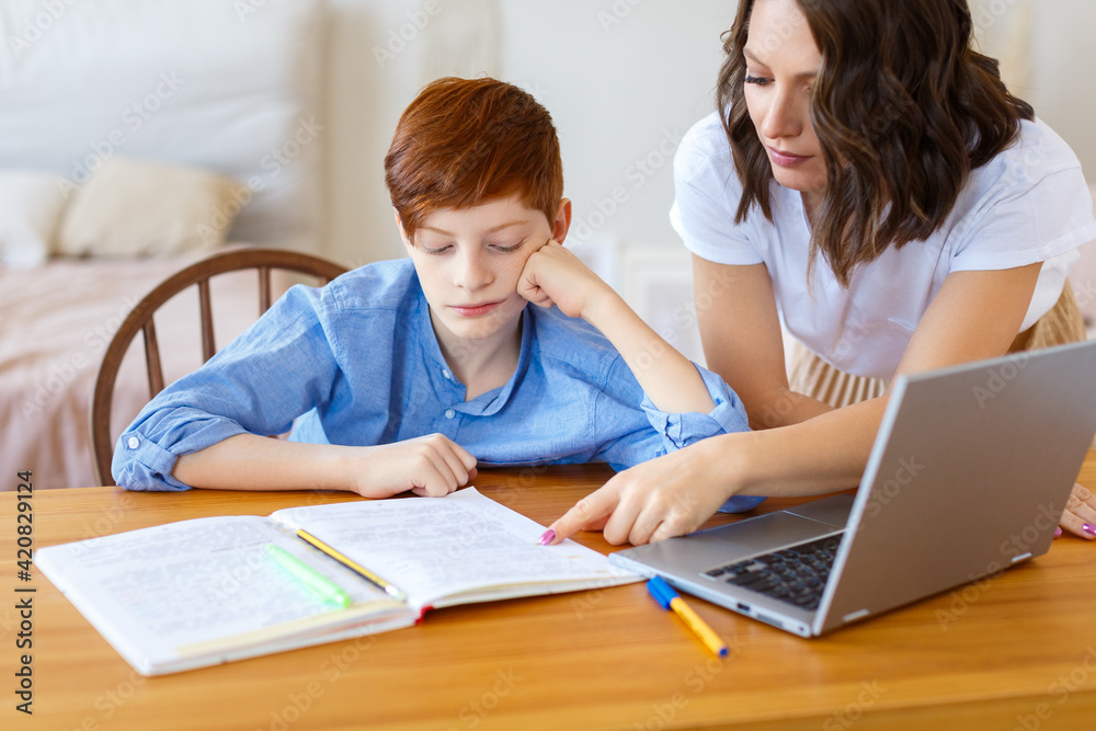 Mom helps her son with online homework. Distant education concept. Selective focus. Mom helps her son with online homework. Distant education concept. Selective focus.
