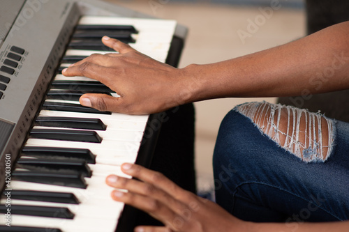 hands only of a young african woman playing a piano