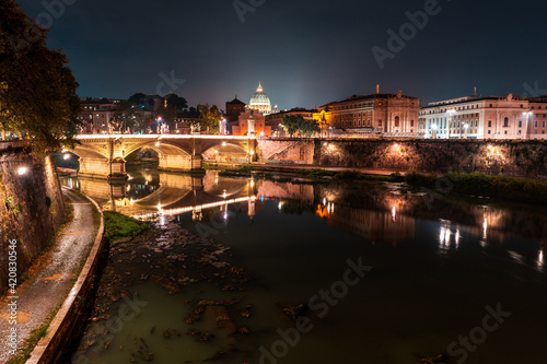 Fotografie Vista nocturna del Río Tiber con cúpula de la basílica de San Pedro iluminada de