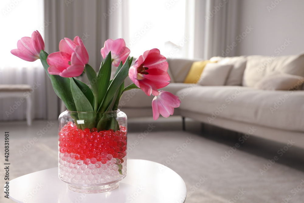 Different color fillers and tulips in glass vase on white table at home,  space for text. Water beads Stock Photo | Adobe Stock