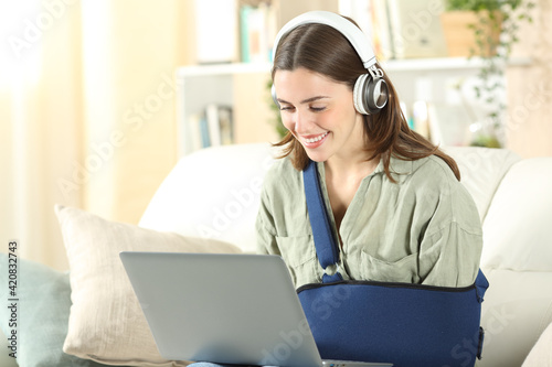 Obraz na plátně Happy disabled woman using laptop and headphones