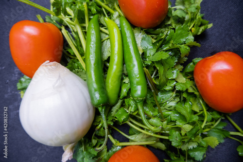 Chili peppers, onion, and a tomato above coriander