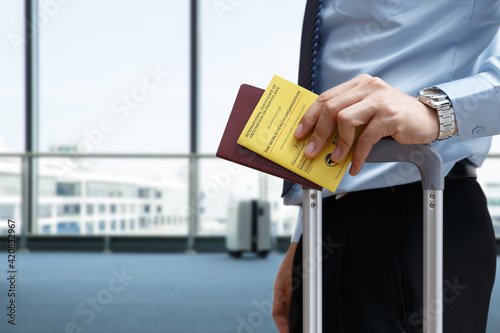 Hand of businessman hold Vaccination Certificate passport for travel or business photo