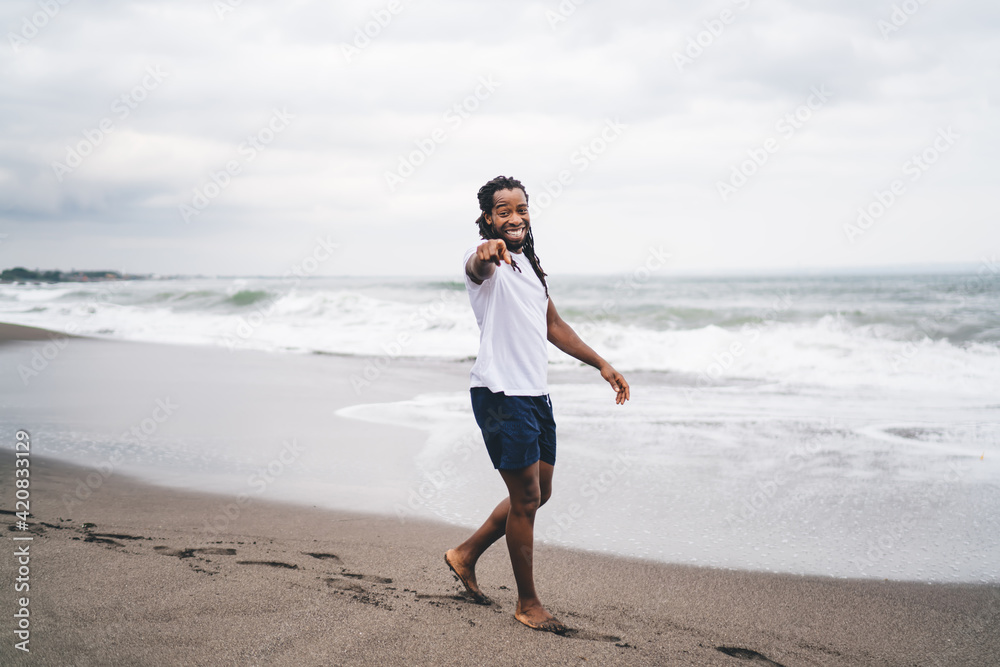 Cheerful black man walking on beach