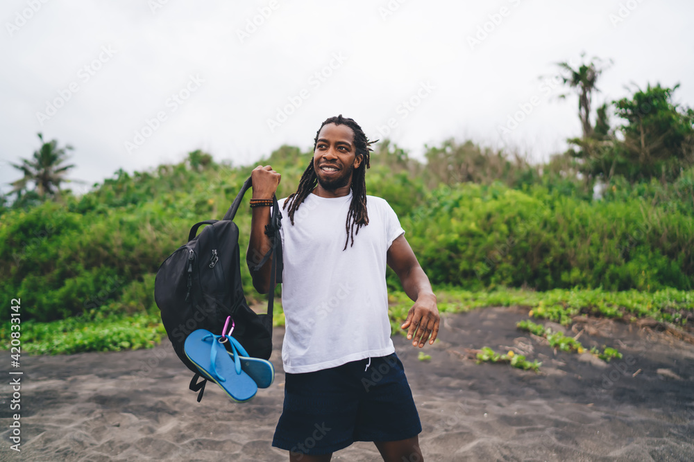 Positive black man with backpack in nature