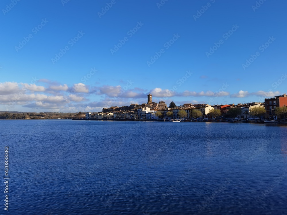 View of a small village on the coastline under a blue sky with scattered clouds.