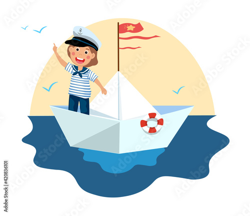 Cute little boy in sailor costume standing on paper boat