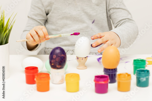 Child is painting eggs with paints on Easter holiday
