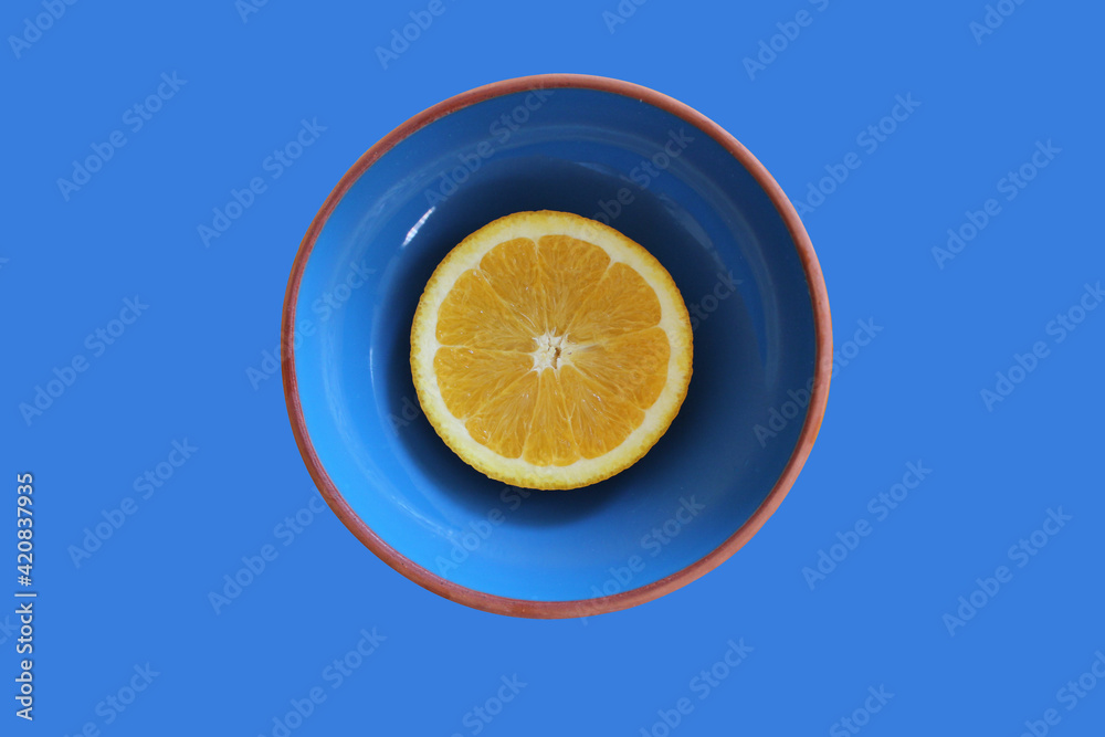 Cut oranges in blue bowl on yellow background. Cut oranges in blue bowl on yellow background.
