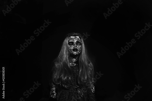 Scary demon doll in the dark. Terrible doll. Dark black background.