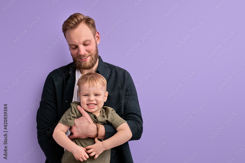 Excited Man With Child Boy In Hands, Posing In Studio On Purple Background Excited Man With Child Boy In Hands, Posing In Studio On Purple Background