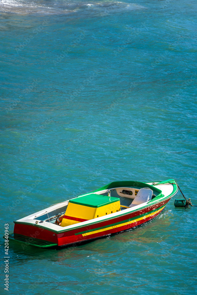 Colorful boat moored in the warm glow of the early evening sun over the  Pacific ocean at Los Muertos Beach, Puerto Vallarta, MX.