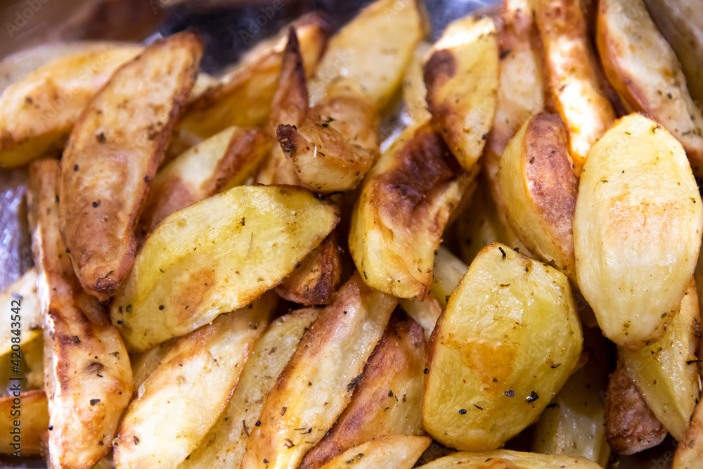 Crispy oven-baked potatoes. Delicious potatoes with herbs for dinner just out of the oven. Close up. Crispy oven-baked potatoes. Delicious potatoes with herbs for dinner just out of the oven. Close up.