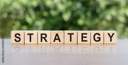 STRATEGY word written on wooden blocks. The text is written in black letters and is reflected in the mirror surface of the table. Business concept for your design