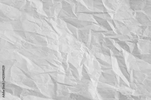 Gray crumpled sheet of rough paper closeup texture blank background.