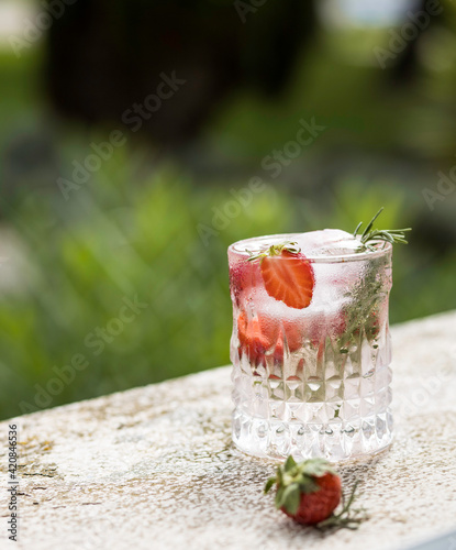 Summer fresh lemonade with strawberries and rosemary in a garten.
Non-alcoholic spargle soda with ice cube and berries photo