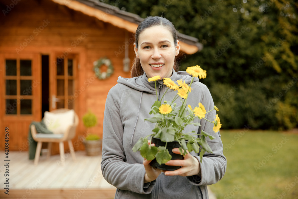 Fototapeta premium Woman holds a plant in her hand and smiles. Gardening is fun. The gardener takes care of the plants and flowers in spring. 