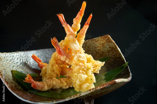 Fried prawn. Shrimp fries in tempura, served in a black Japanese-style bowl. Isolated on a black background. Restaurant food - seafood