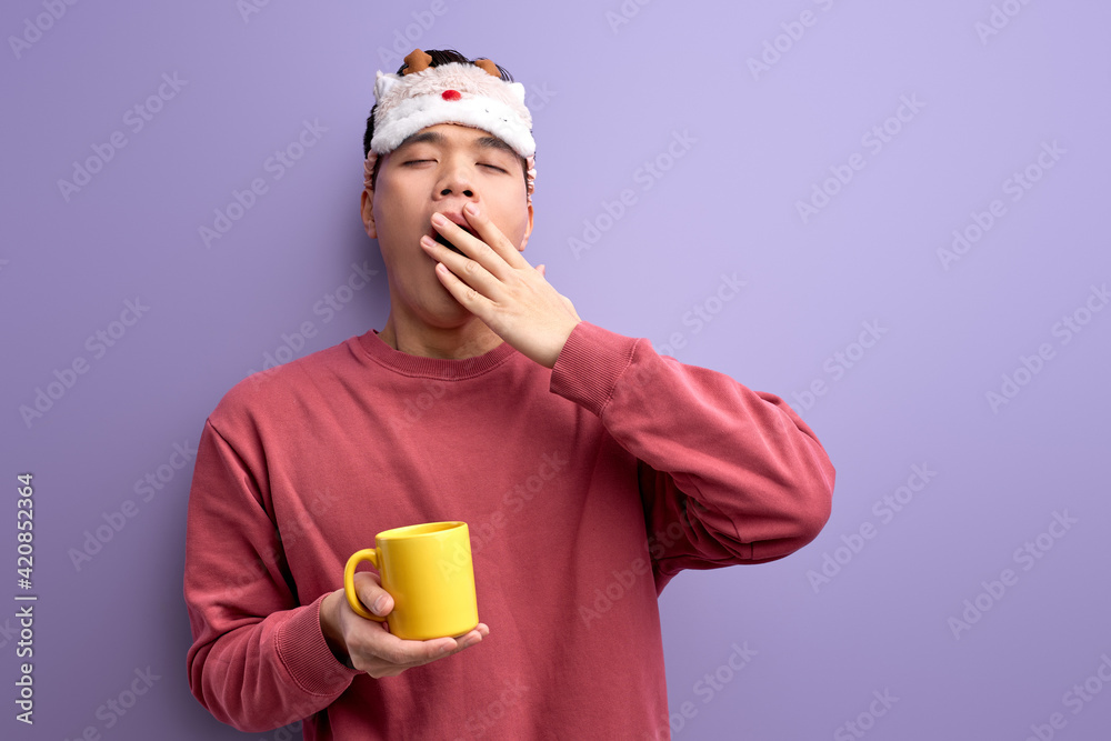exhausted asian student with mug in hands yawning, want to sleep before school or university exhausted asian student with mug in hands yawning, want to sleep before school or university