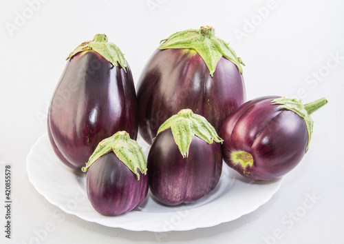 A group of eggplant on a white plate on a white background.