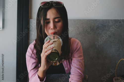 Girl hold plastic cup of ice matcha and use straw to drink