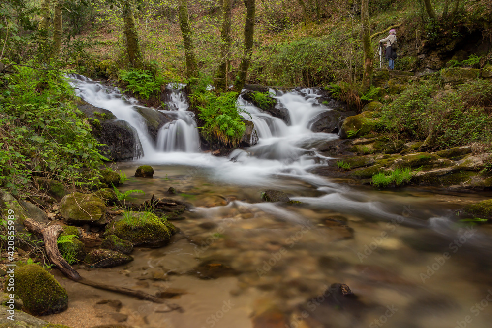 Fototapeta premium waterfalls inside the forest with a photographer
