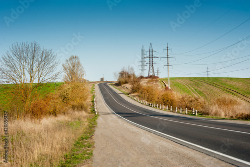 Early spring scene with trees, green fields and a big road stretching between...