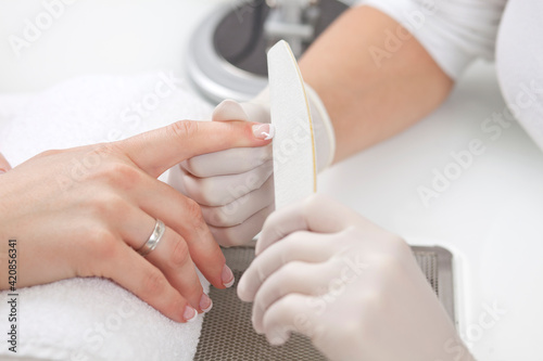 closeup of female hand getting nail manicure by professional manicurist