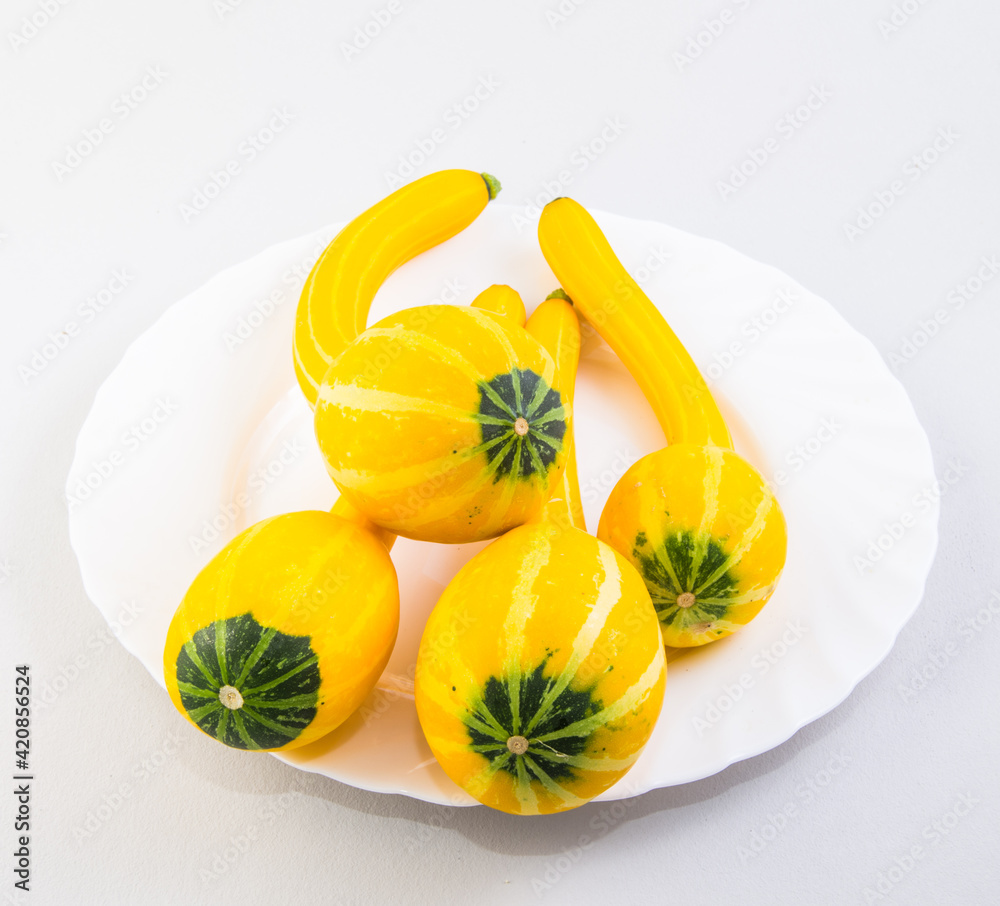 Fresh raw yellow zucchini on a white plate isolated on a white background