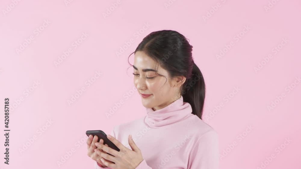 Beauty concept of 4k Resolution. Asian girl playing mobile phone on pink background. Beauty concept of 4k Resolution. Asian girl playing mobile phone on pink background.