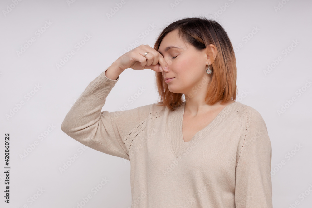 Young woman feels disgust pinches her nose with fingers because of unpleasant stink. Young woman feels disgust pinches her nose with fingers because of unpleasant stink.