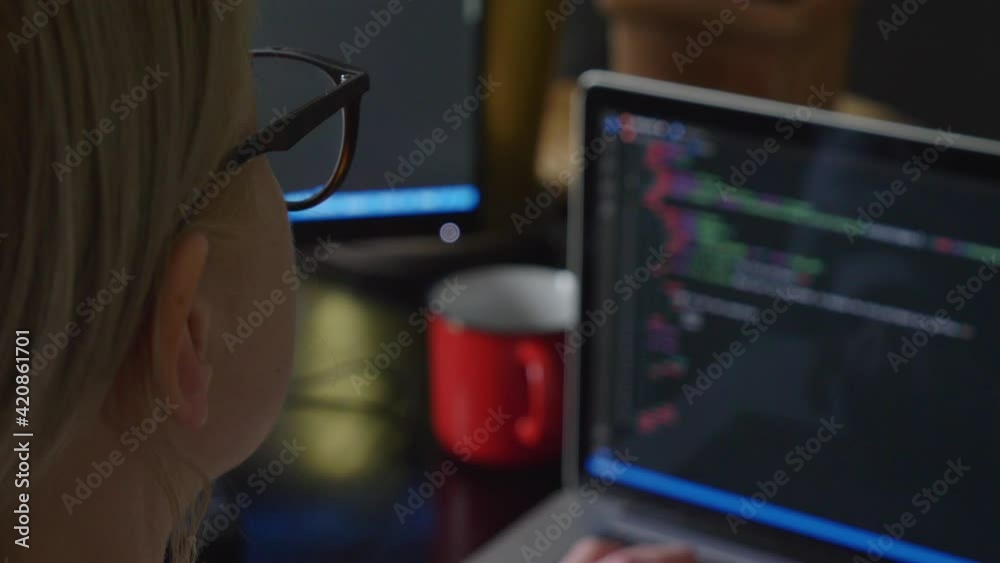 View as woman in glasses working with code on laptop computer. View as woman in glasses working with code on laptop computer.
