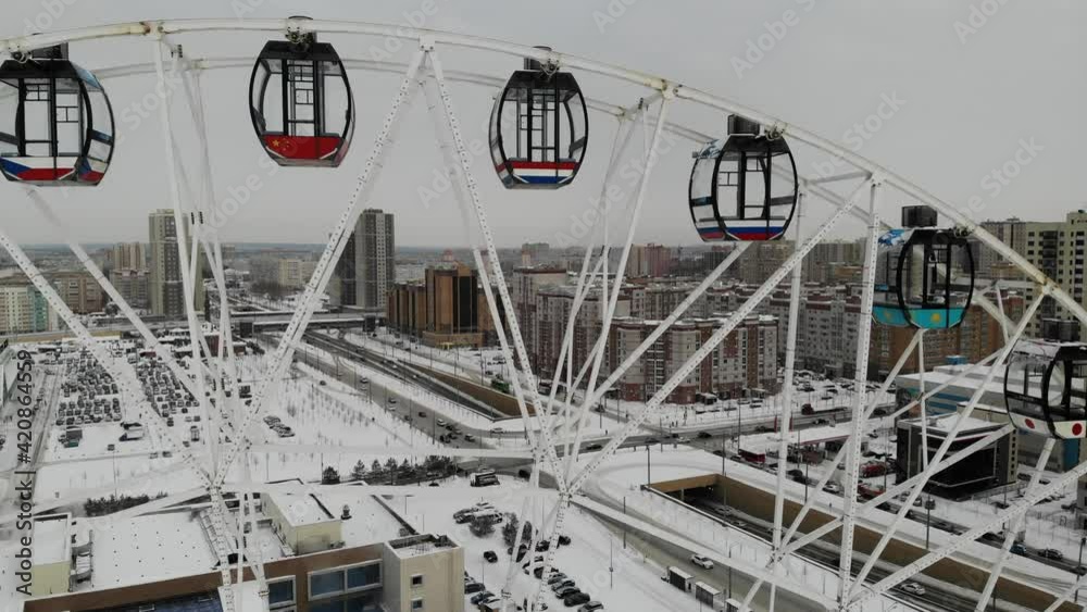 Rotating Ferris wheel in Tatarstan Kazan at winter. Snow covered pool under near aquapark. Aerial drone view. Flying over. Drone is standing Rotating Ferris wheel in Tatarstan Kazan at winter. Snow covered pool under near aquapark. Aerial drone view. Flying over. Drone is standing