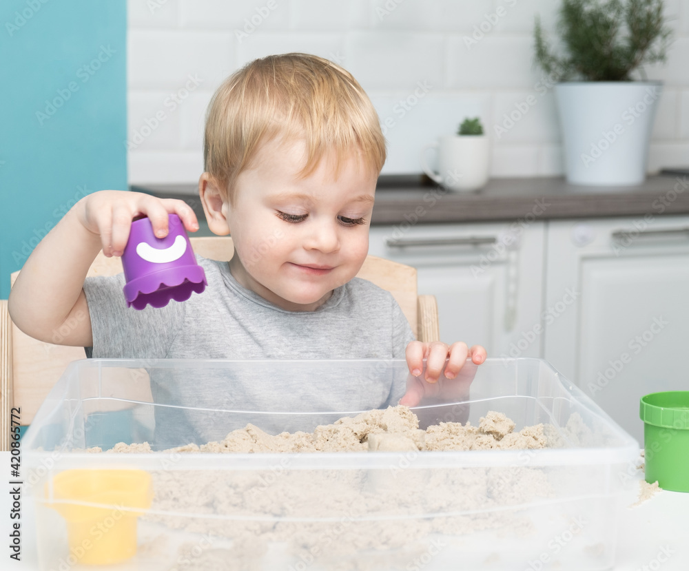 little blonde boy playing with kinetic sand at home. Early age education. Toddler playing little blonde boy playing with kinetic sand at home. Early age education. Toddler playing