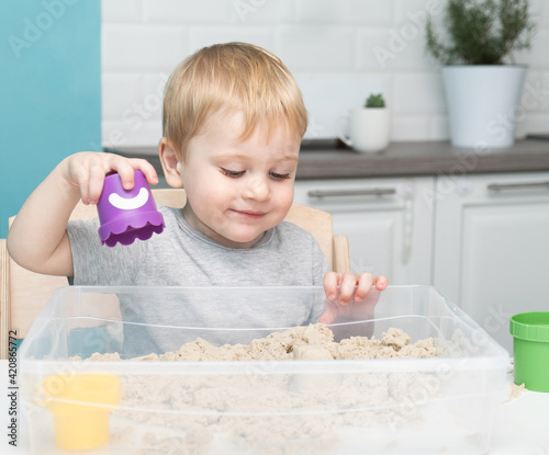 little blonde boy playing with kinetic sand at home. Early age education. Toddler playing