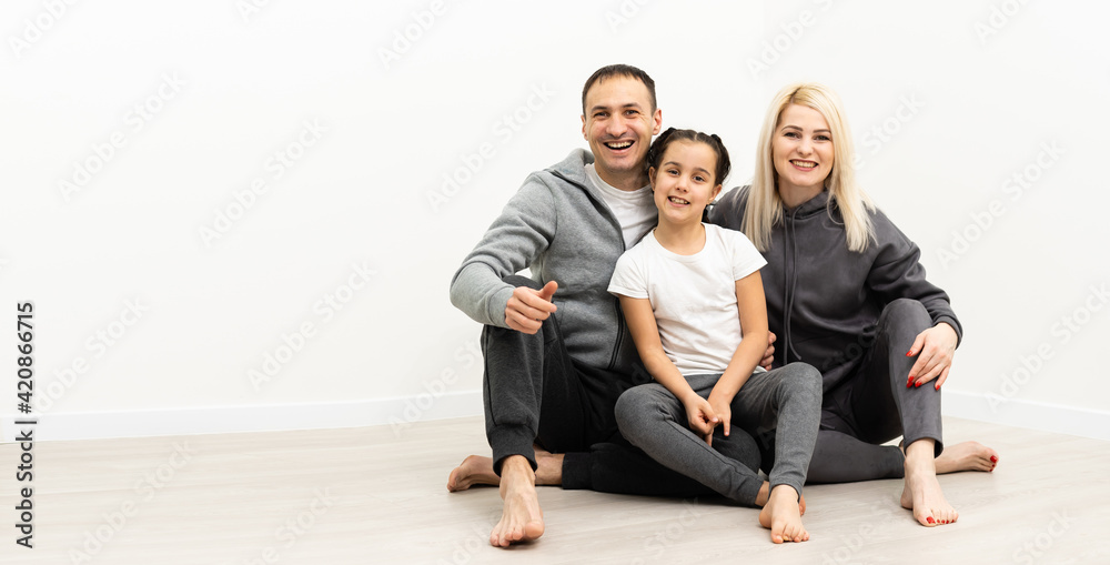 happy family father mother and children sitting on the floor in an empty white wall