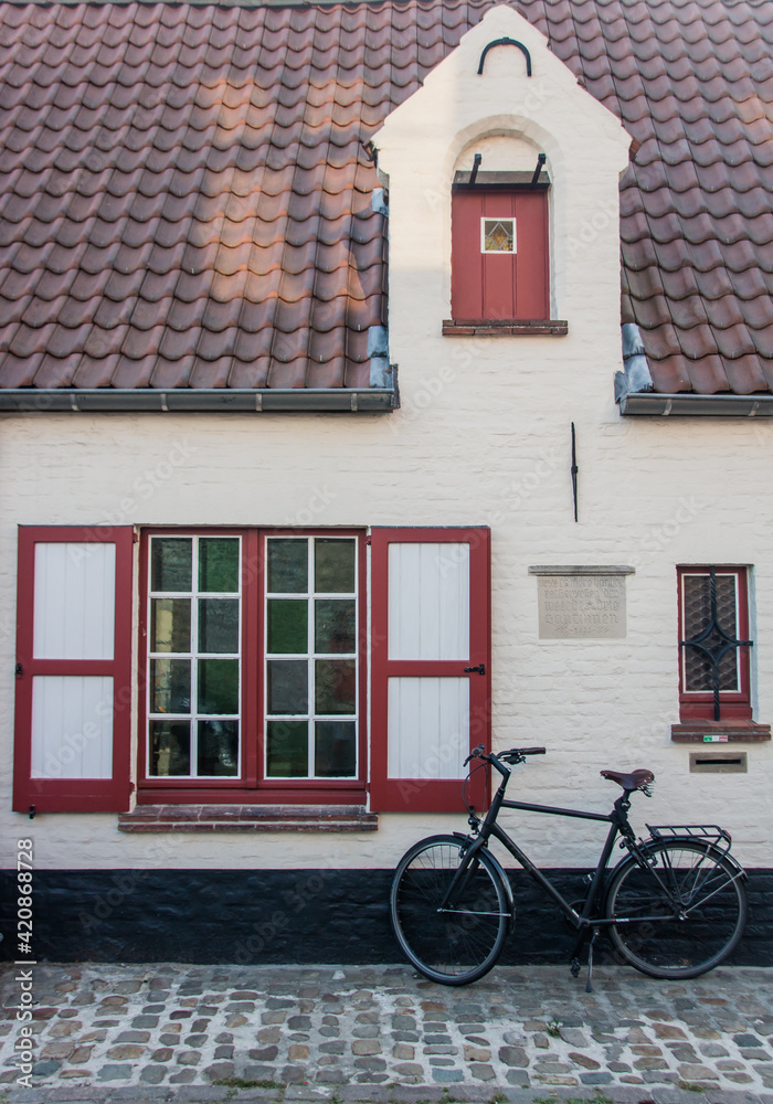 maison flamande avec des volets rouges et un vélo garé devant maison flamande avec des volets rouges et un vélo garé devant