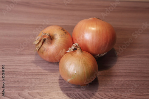 Three onions on a wooden table. Soft focus