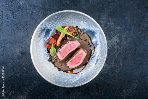 Modern style Italian tagliata di manzo with dry aged sliced sirloin steak and tried vegetable in truffle sauce served as top view in a design ceramic bowl with copy space