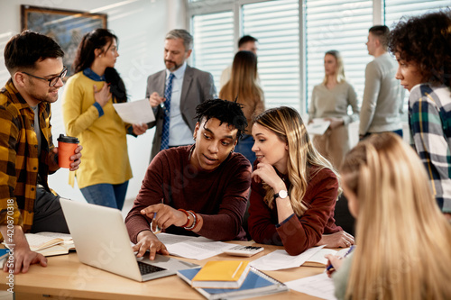 College students cooperating while suing laptop in the classroom.